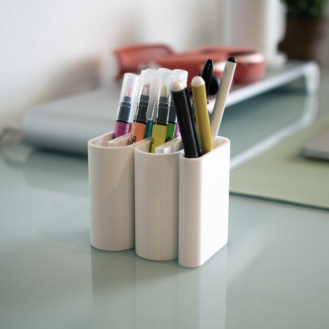 a white cup with pens and markers in it