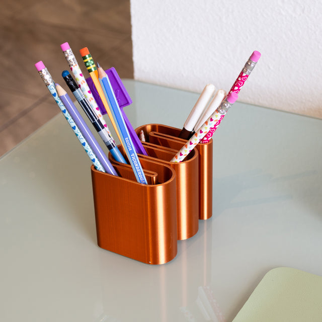 a set of four pencils sitting in a cup on a table