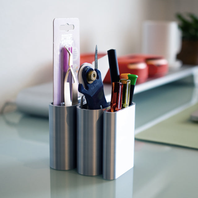 a pen holder with pens, scissors, and other office supplies