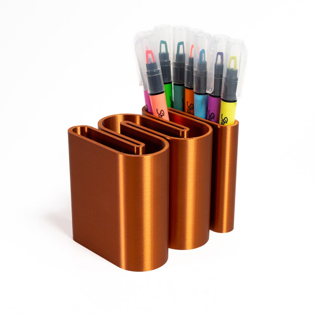 a set of four pens and markers in a holder