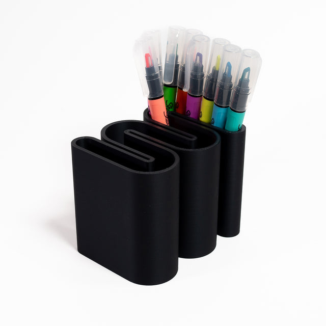 a set of four pens and markers in a holder